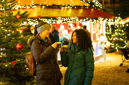 Zwei Frauen trinken Glühwein auf dem Weihnachtsmarkt