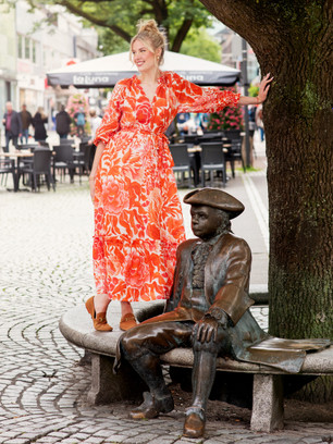 Fotoshooting mit Frau, die neben einer Statue auf einer Bank in der Kieler Innenstadt steht 