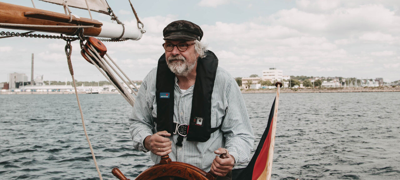 Segler hält Steuerrad von Segelboot in der Hand