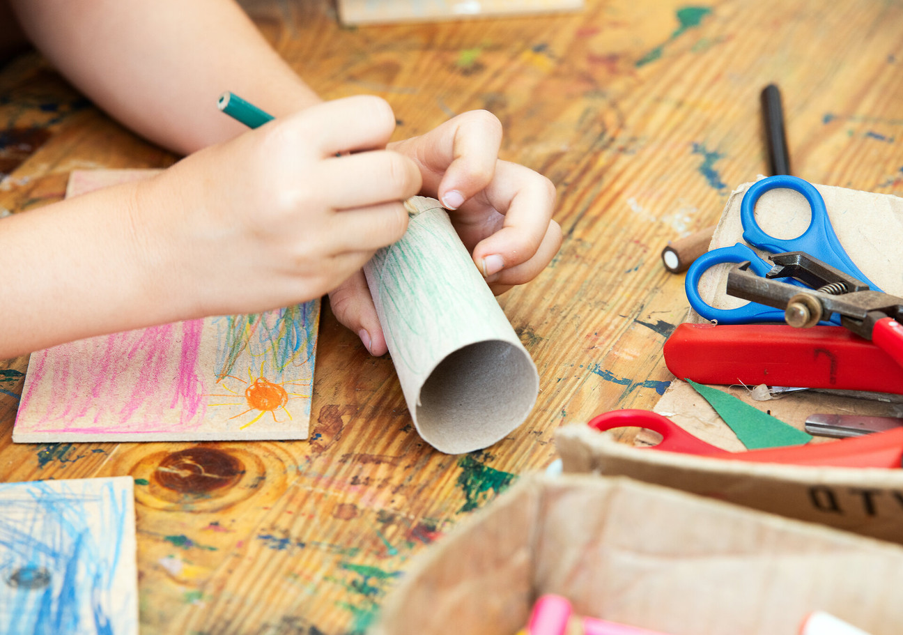 Eine Kinderhand bemalt eine Papprolle