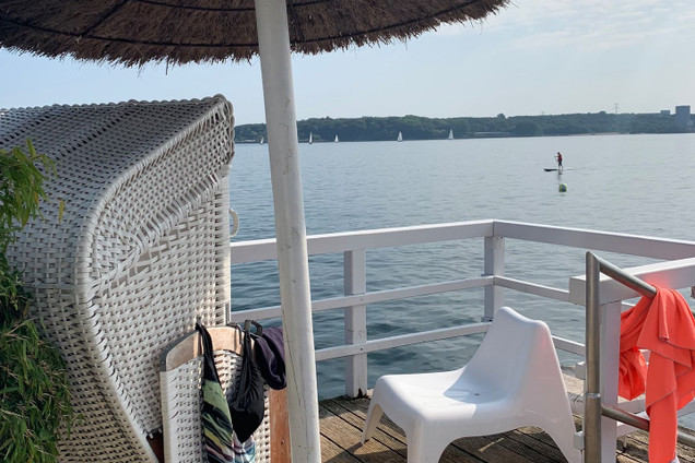 Seebar Düsternbrook Kiel: Steg mit Strandkorb, Stuhl und Schirm, Hintergrund Meer