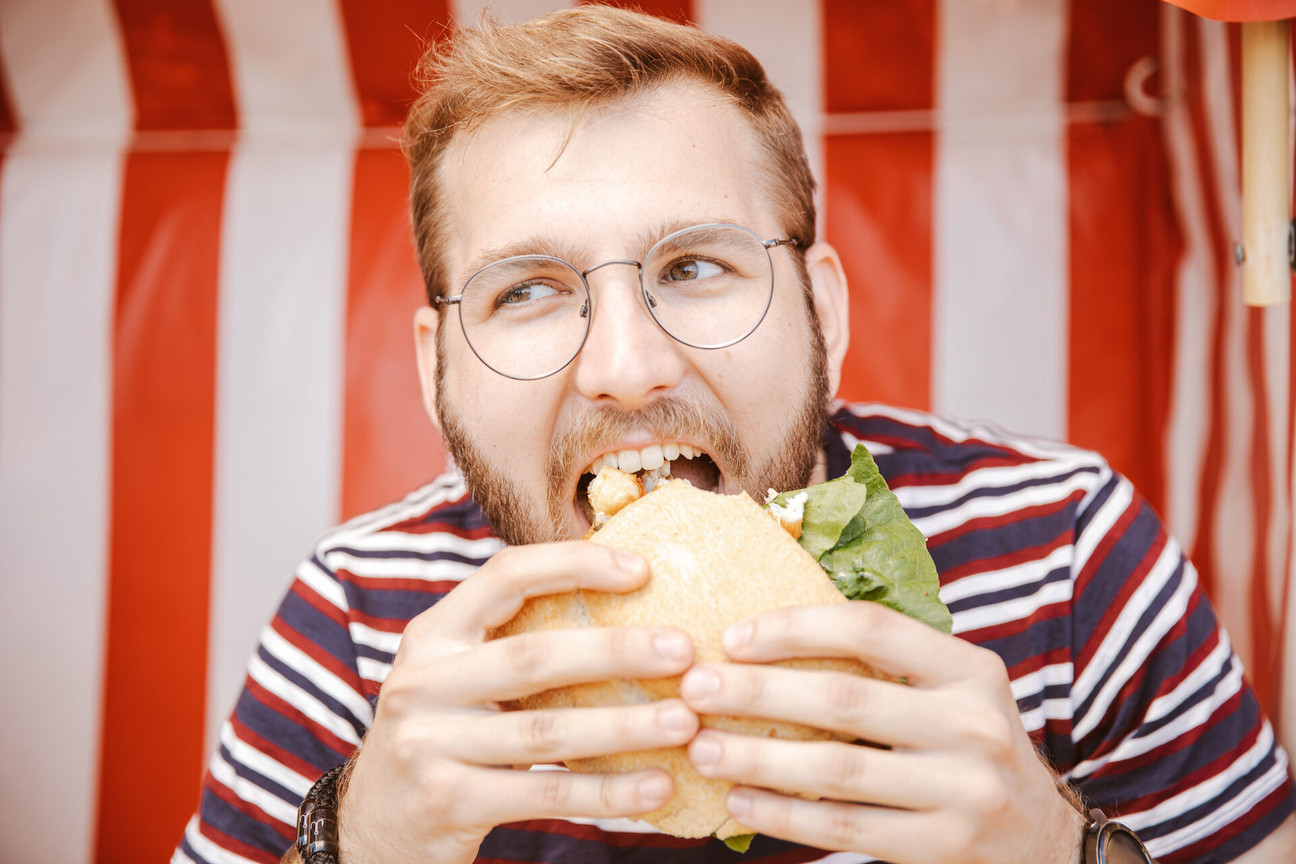Mann beißt in Fischbrötchen