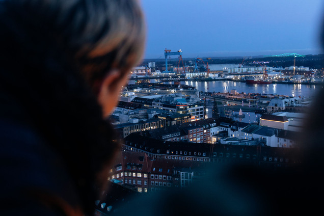 Frau steht auf dem Rathausturm und macht ein Foto von der Skyline
