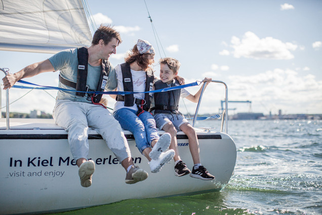 Eine Familie sitzt auf einem Segelboot und segelt auf der Kieler Förde