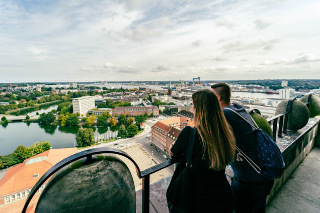 Paar blickt auf dem Kieler Rathausturm über die Dächer der Stadt