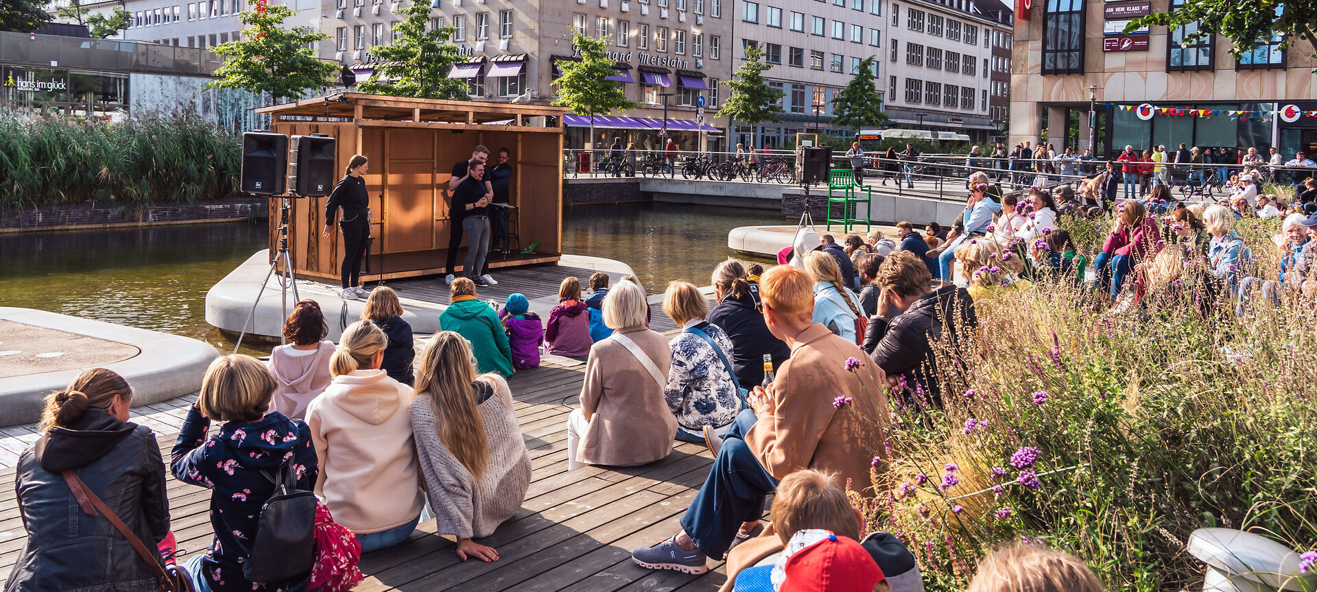 Menschen sitzen am Fleet und schauen dem Theater zu