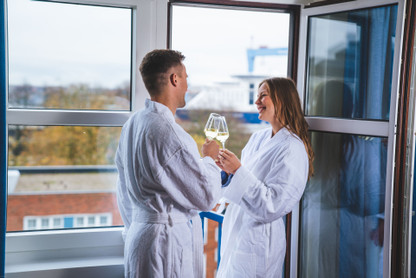 Pärchen in Bademantel trink Sekt und genießt Aufenthalt im Hotel mit Ausblick