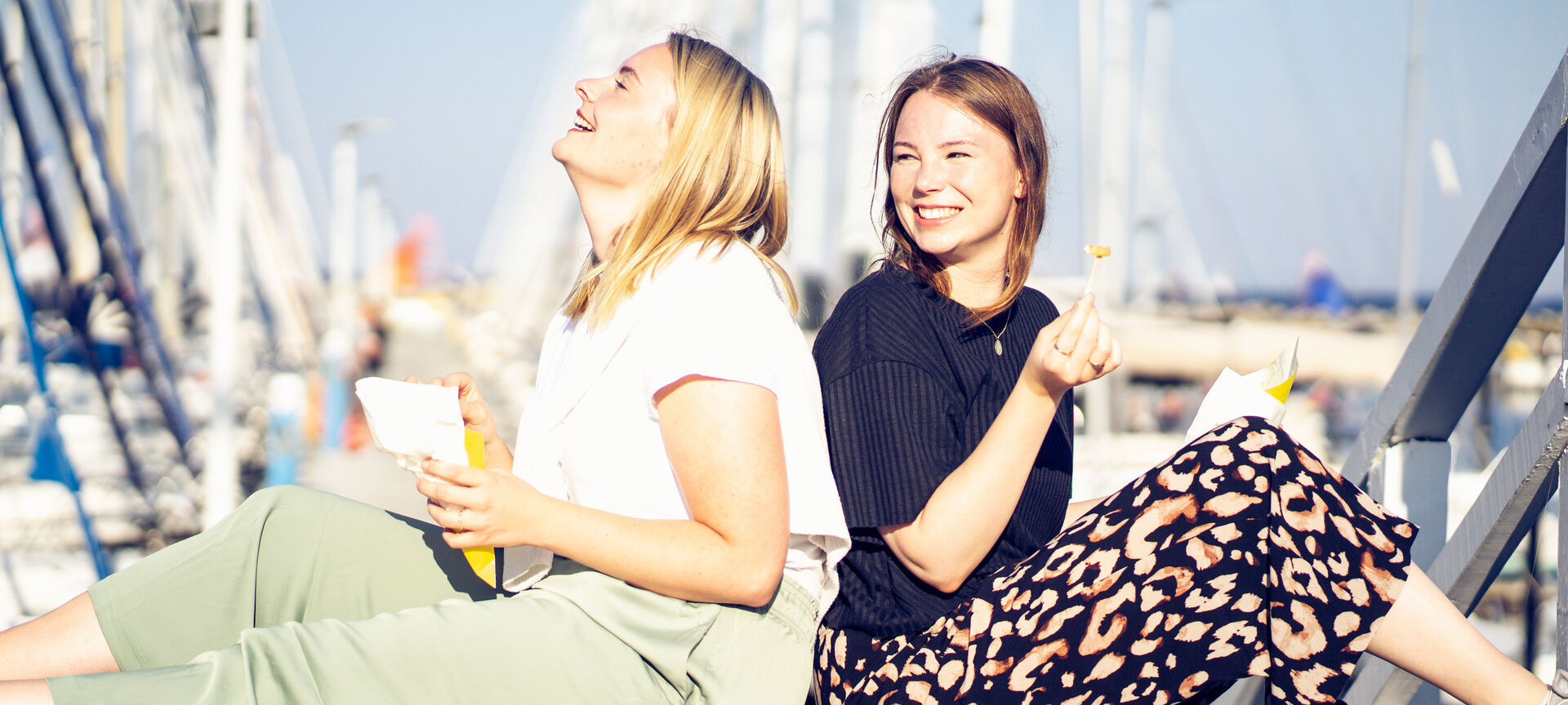 Zwei Frauen sitzen am Hafen in Schilksee und essen etwas