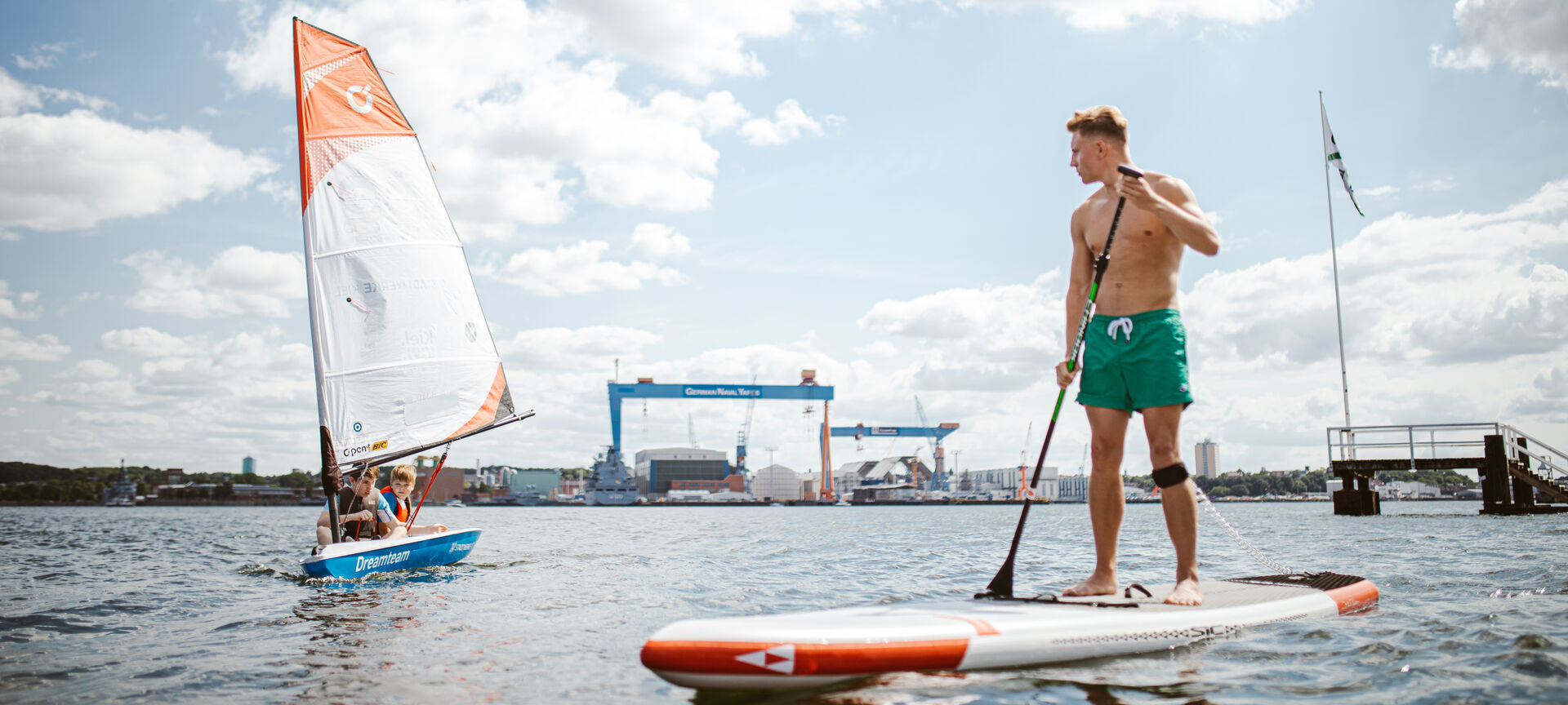 Segel-Opti und SUP-Fahrer auf der Kieler Förde