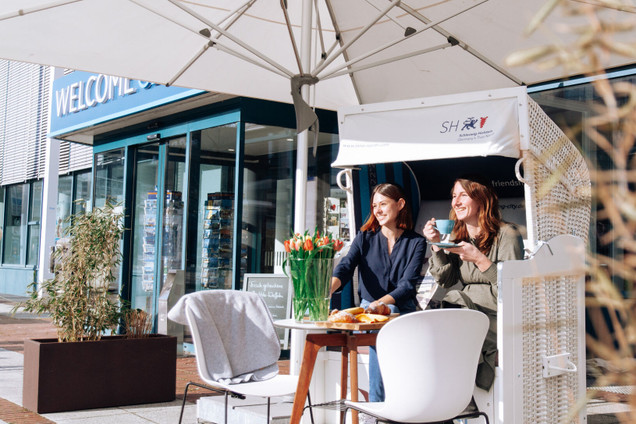 Zwei Frauen trinken Kaffee im Strandkorb vor dem Welcome Center