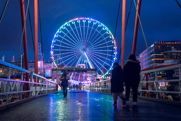 Menschen auf der Brücke und Riesenrad im Hintergrund