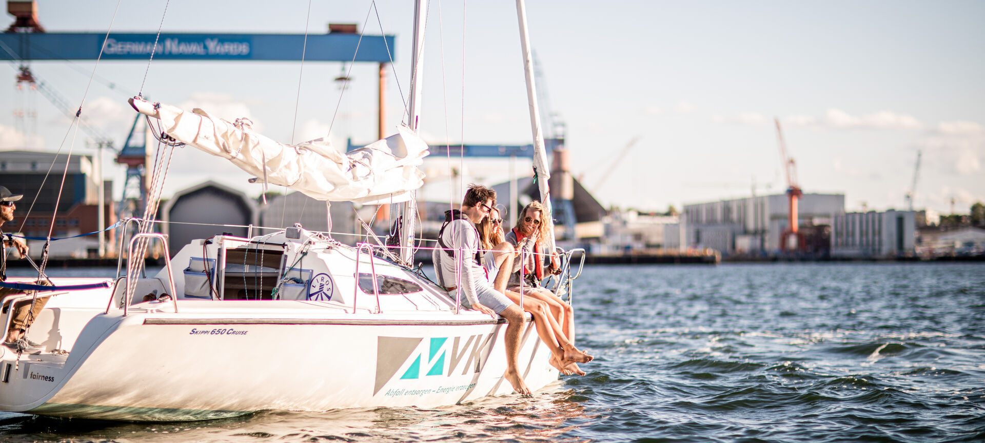 ein Mann und zwei Frauen auf einer Skippi Yacht an einem sonnigen Spätnachmittag auf der Kieler Förde