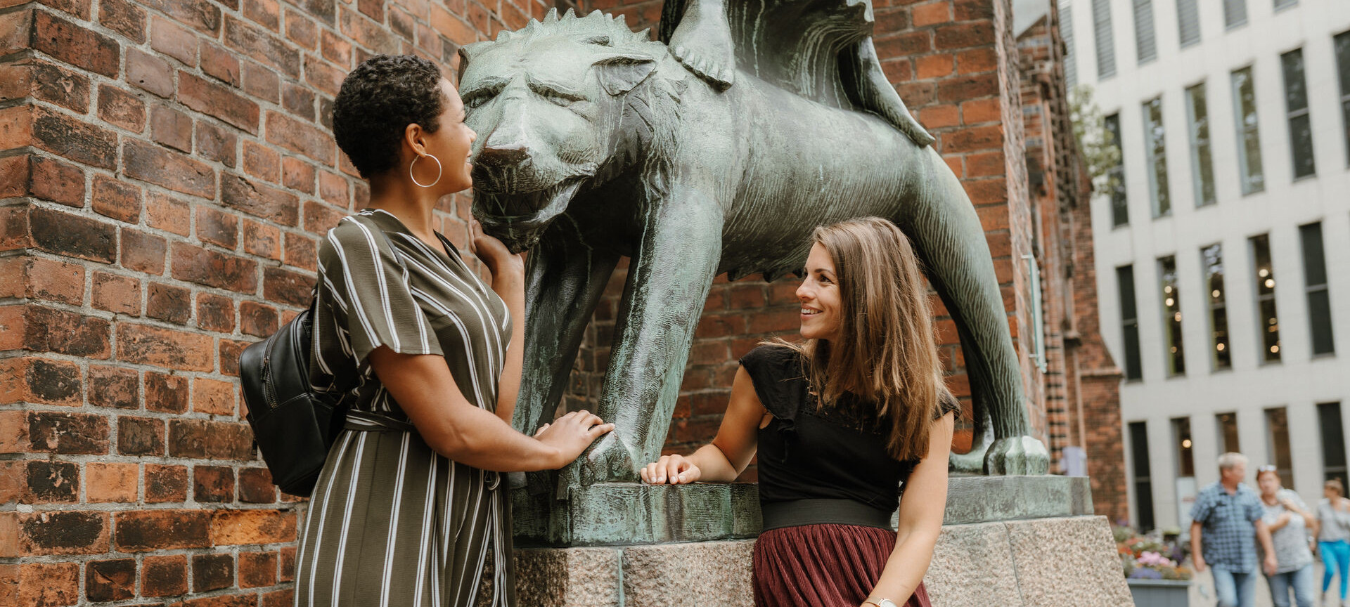 Two women are standing in front of a statue and talking. 