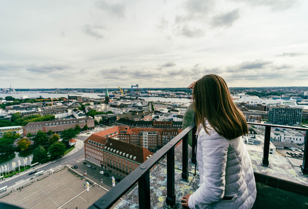 Woman in jacket looks from the town hall tower over kiel