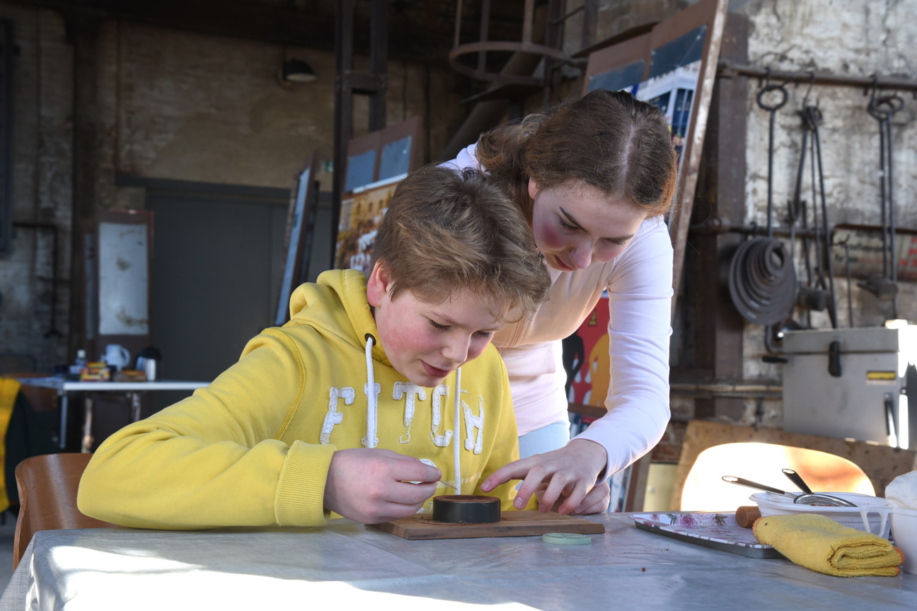 Eine Frau hilft einem Jungen beim Guss-Workshop