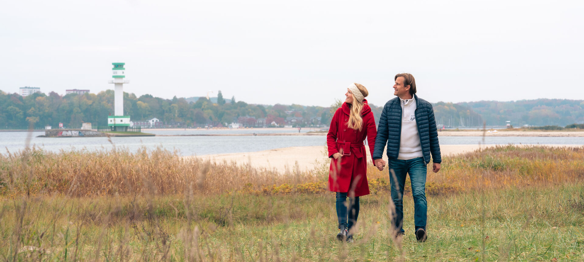 Ein Paar läuft im Herbst am Strand entlang