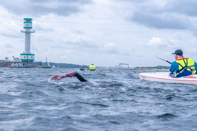 Schwimmer*innen und Kanufahrer*innen im Wasser vor dem Friedrichsdorfer Leuchtturm