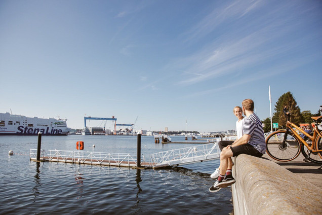 Paar sitzt an der Kiellinie mit Blick auf die Kieler Förde
