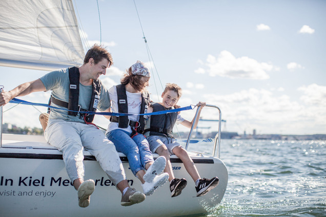 Vater, Mutter und Kind auf einem Segelboot an einem sonnigen Tag an der Kieler Förde